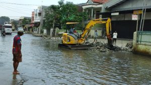 Alat berat sedang melakukan pengerukan saluran air.